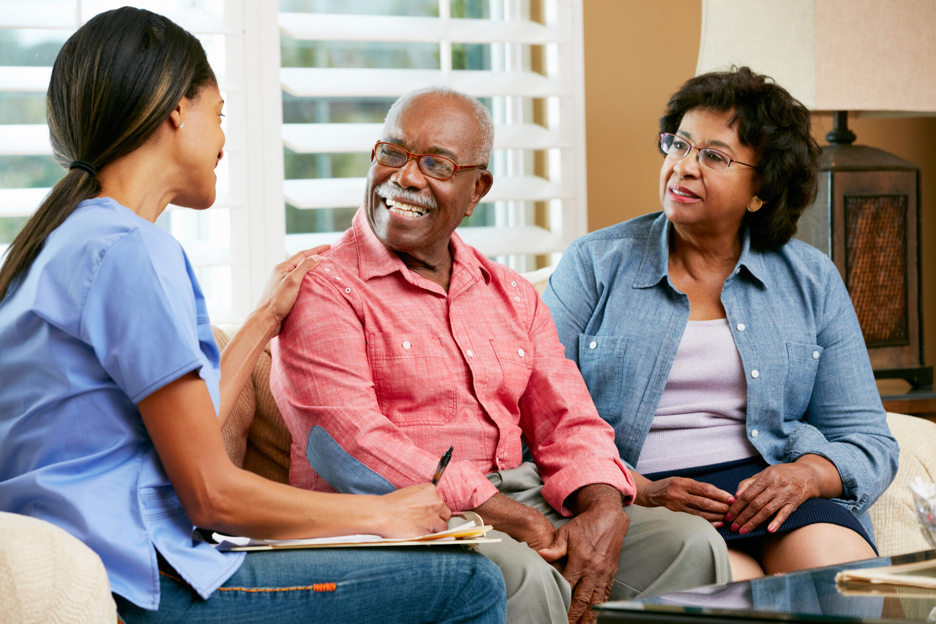 Nurse making notes during a home visit with senior patients